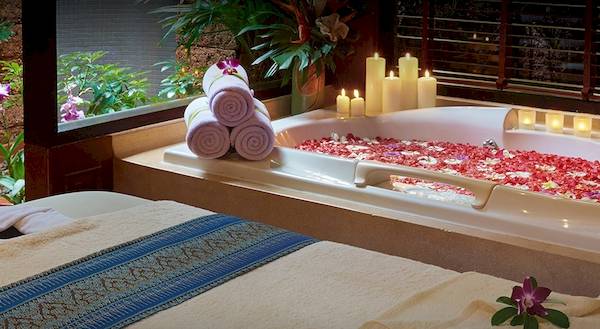 Badewanne im Bo Phut Resort & Spa mit roten Blumen und Kerzenlicht.