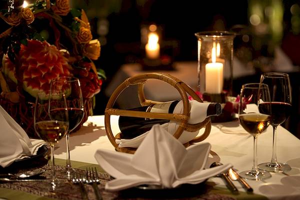 Ein elegant gedeckter Tisch im Bo Phut Resort & Spa mit Weinflaschen und Kerzenlicht.