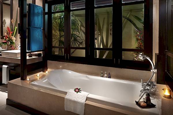 Badezimmer im Bo Phut Resort & Spa mit Badewanne, Waschbecken und Fenstern.