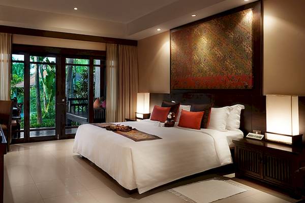 Schlafzimmer im Bo Phut Resort & Spa mit Doppelbett, Glastüren und Gartenblick.