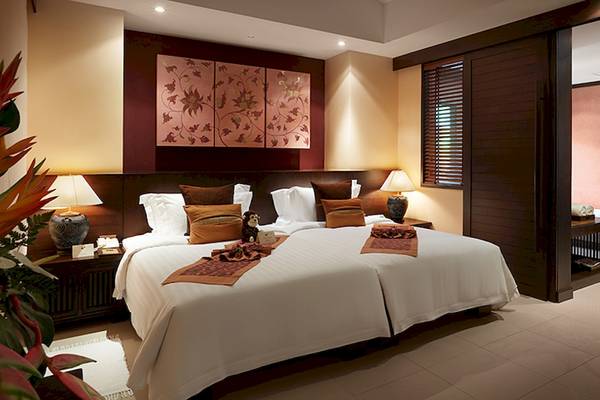 Schlafzimmer im Bo Phut Resort & Spa mit zwei Betten, Kissen, Lampen und Dekoration.