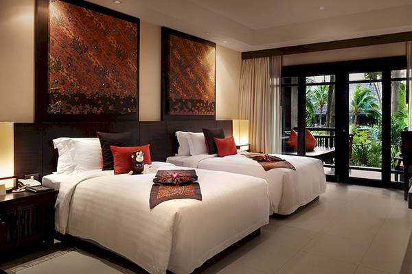 Doppelzimmer im Bo Phut Resort & Spa mit zwei Betten, roten Kissen und einem Blick auf einen Garten.