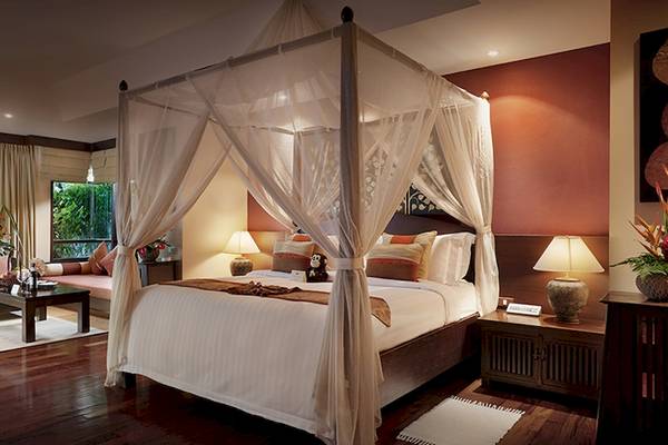 Schlafzimmer im Bo Phut Resort mit Himmelbett, zwei Nachttischen und Lampen.