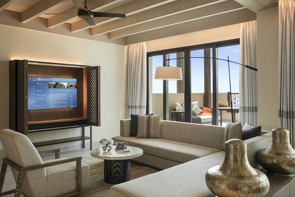 Innenansicht des Wohnzimmers im Saadiyat Rotana Resort & Villas mit Fernseher, Couch, Tisch und Vasen.
