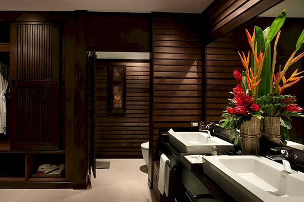 Badezimmer im Bo Phut Resort & Spa mit zwei Waschbecken, Toilette, Spiegel und Holzverkleidung.