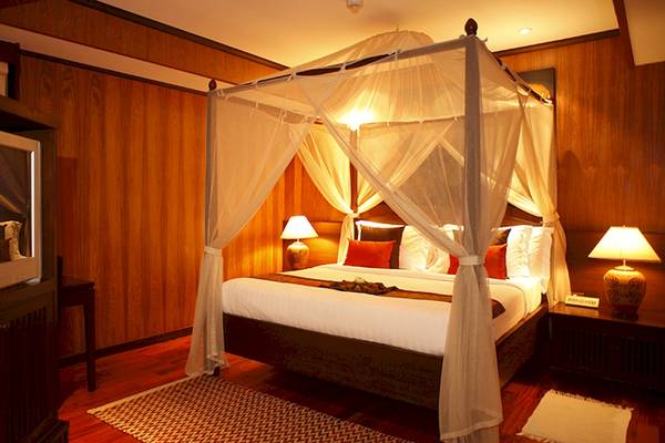 Schlafzimmer im Bo Phut Resort & Spa mit Himmelbett, Fernseher und Nachttischen.
