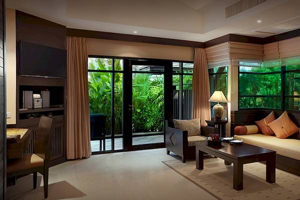 Innenansicht des Wohnbereichs im Bo Phut Resort & Spa mit großem Fenster, Sofa und Tisch.