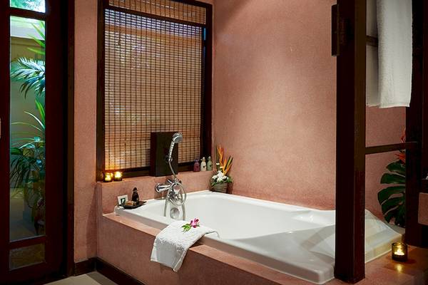 Badezimmer im Bo Phut Resort & Spa mit Badewanne, Dusche, Toilettenartikeln und Pflanzen.