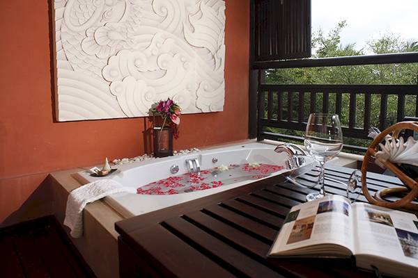 Auf einem Balkon befindet sich eine Badewanne mit Blumen und einem offenen Buch.