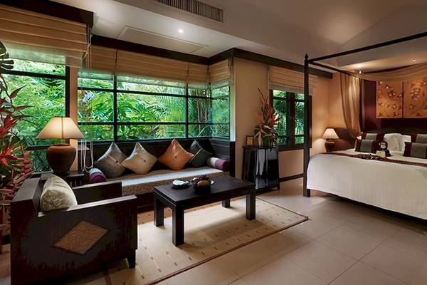 Schlafzimmer im Bo Phut Resort & Spa mit vierposter-bett, sitzecke, tisch, lampen und pflanzen im hintergrund