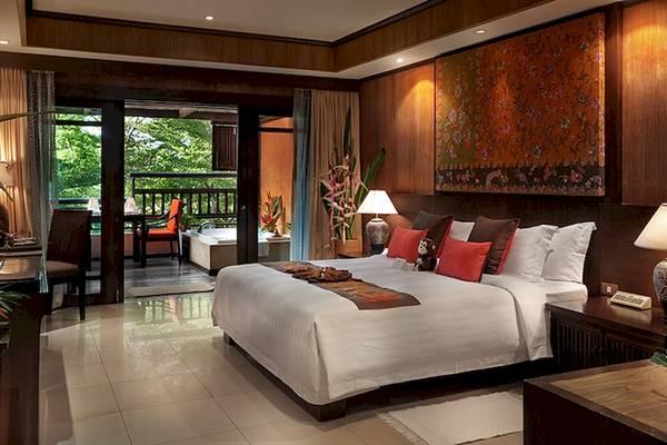 Schlafzimmer im Bo Phut Resort & Spa mit einem großen Bett, Kissen und einem Balkon mit Aussicht auf den Garten.