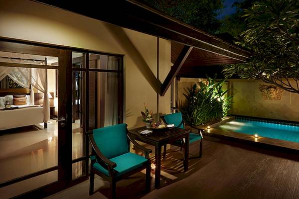Terrasse des Bo Phut Resort & Spa mit einem Bett, Tisch und Swimmingpool.