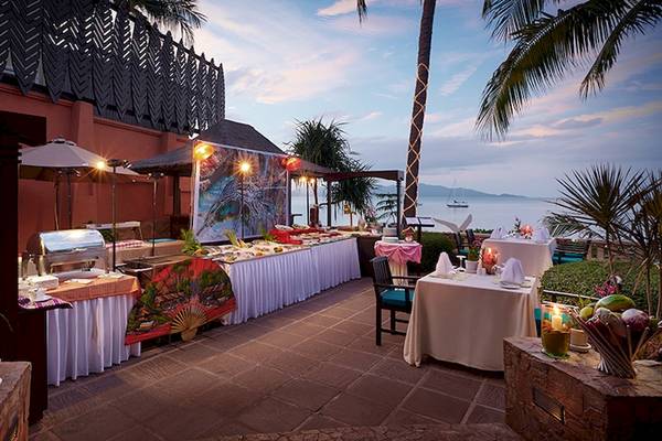 Außenbereich des Bo Phut Resort & Spa mit einem Abendessen-Buffet am Strand.