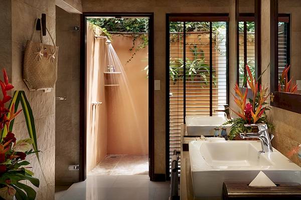 Badezimmer im Bo Phut Resort & Spa mit Dusche und Badewanne, Pflanzen und Blumen.