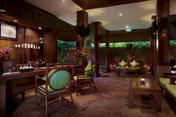 Innenbereich des Bo Phut Resort & Spa mit Holzmöbeln, grünen Kissen und Kerzen.