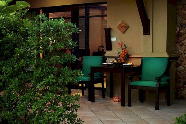 Terrasse des Bo Phut Resort & Spa mit grünen Stühlen und Tisch, dekoriert mit Früchten und Lampion.