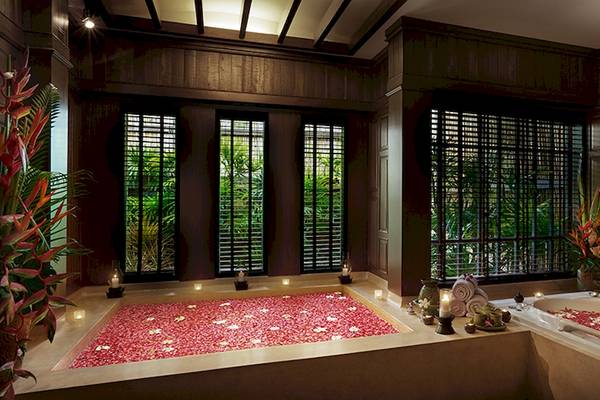 Innenansicht des Bo Phut Resort & Spa mit einer Badewanne voller roter Blütenblätter.