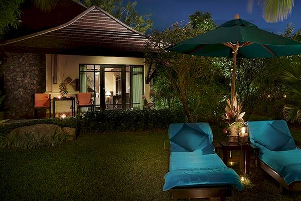 Zwei blaue Liegen unter einem grünen Schirm im Garten des Bo Phut Resort & Spa