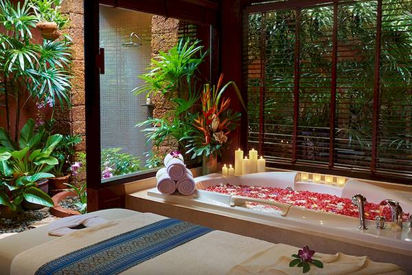 Jacuzzi im Bo Phut Resort & Spa mit Blumen und Kerzen, Blick auf die Außenlandschaft.