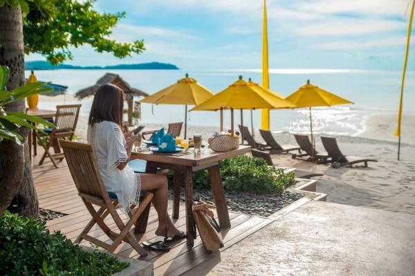 Frau sitzt am Tisch am Strand des Hotels Buri Rasa Village Samui