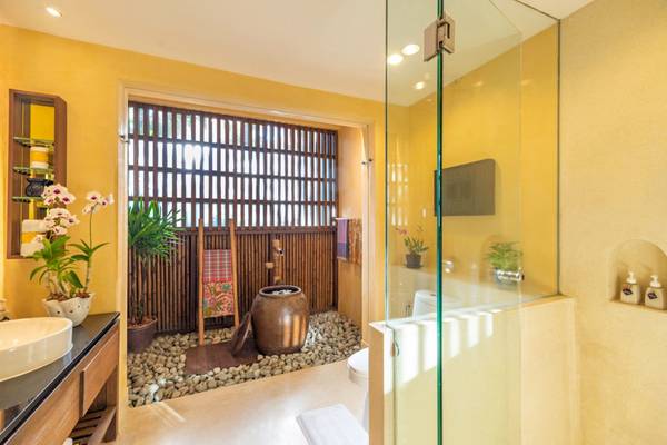Badezimmer im Buri Rasa Village Samui mit Regendusche und Pflanzen.