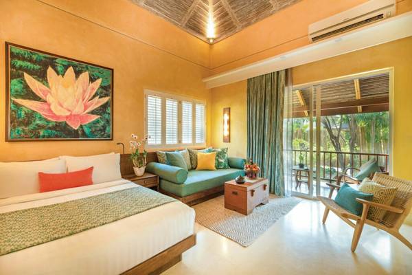 Innenansicht eines Hotelzimmers im Buri Rasa Village Samui mit einem Bett, einem Sofa und einem Balkon.