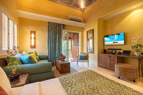 Innenansicht einer Suite im Buri Rasa Village Samui mit einem Bett, Sofa, Fernseher und Balkon
