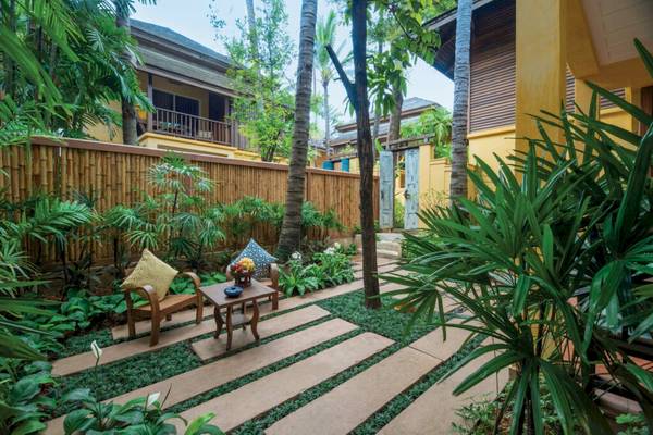 Gartenbereich des Buri Rasa Village Samui Hotels mit Möbeln und Pflanzen.