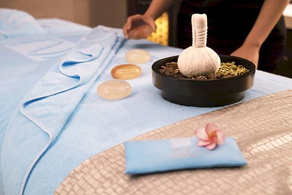 Massagetisch im Saadiyat Rotana Resort mit drei Steinen, einem Beutel und einer Blume.