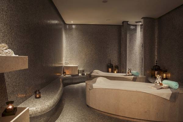 Wellnessbereich im Saadiyat Rotana Resort & Villas mit Marmorwänden, Liegen und Lampen.
