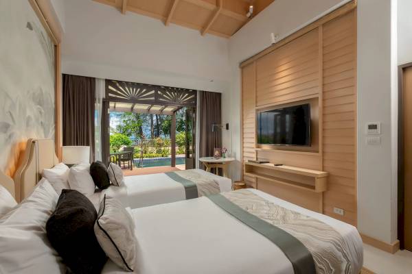 Innenansicht eines Zimmers im Khao Lak Merlin Resort mit zwei Betten, Fernseher und Poolblick.