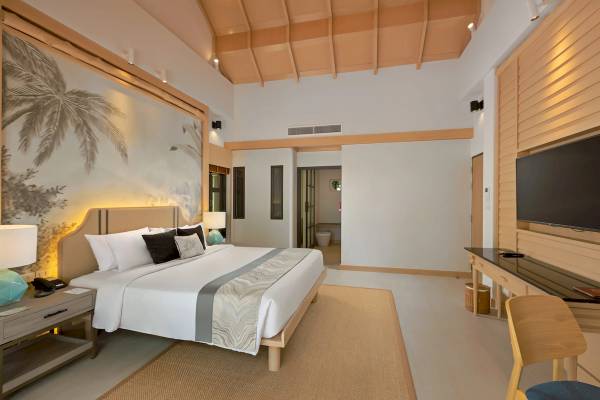 Innenansicht eines Zimmers im Khao Lak Merlin Resort mit einem Bett, Schreibtisch und Fernseher.