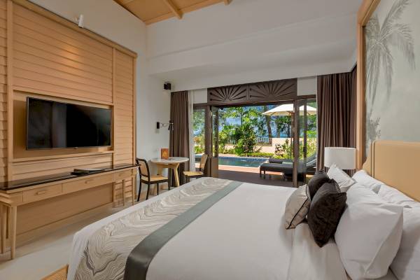 Schlafzimmer im Khao Lak Merlin Resort mit Bett, Fernseher und Blick auf den Pool.