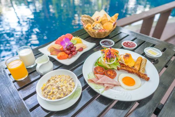 Frühstücksbuffet am Pool des Khao Lak Merlin Resorts mit verschiedenen Gerichten, Obst und Getränken.