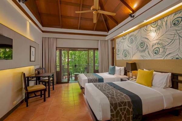 Doppelbett-Zimmer im Khao Lak Merlin Resort mit zwei Betten, Tisch, Stühlen und Balkon.