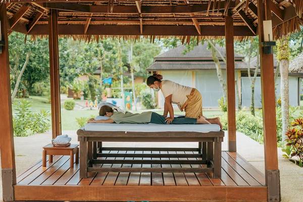 Massage im Pavillon im Khao Lak Merlin Resort mit einer Frau, die einen Mann massiert.