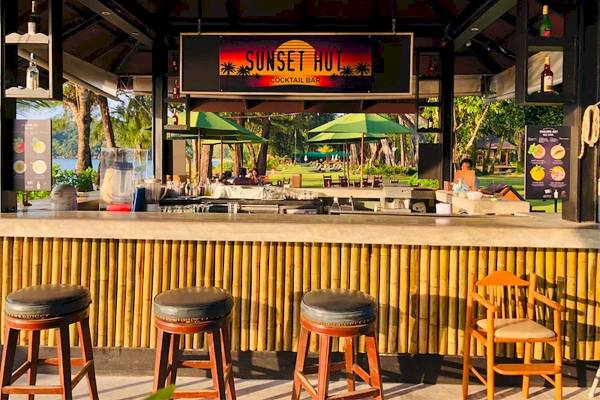 Cocktailbar im Khao Lak Merlin Resort mit Sonnenuntergangs-Thema und grünen Sonnenschirmen.