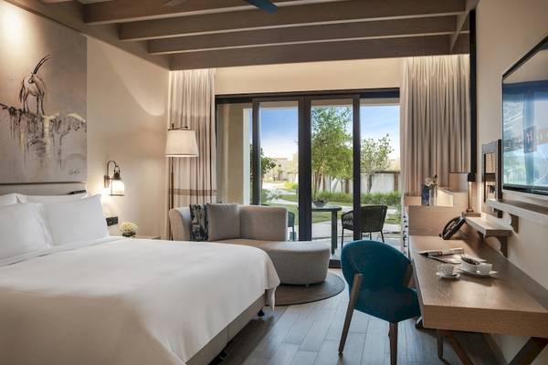 Ein elegantes Schlafzimmer im Saadiyat Rotana Resort & Villas mit Blick auf einen Garten.