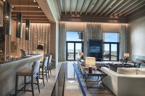 Wohnzimmer des Saadiyat Rotana Resort & Villas mit Bar, Sofas, Fernseher und großen Fenstern.