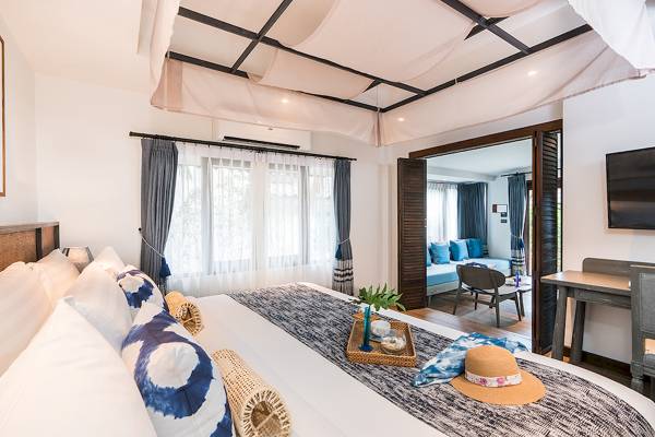Schlafzimmer im Peace Resort mit Bett, Kissen, Deko und offenem Zugang zum Wohnzimmer
