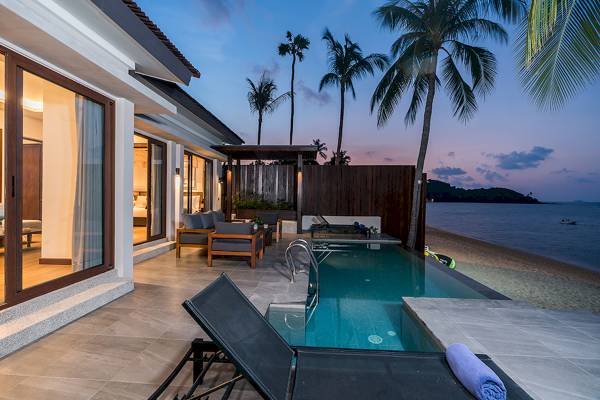 Strandvilla mit Swimmingpool und Loungebereich bei Sonnenuntergang, Palmen im Hintergrund