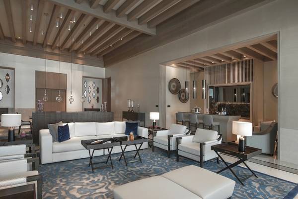 Ein eleganter Saal im Saadiyat Rotana Resort & Villas mit weißen Möbeln, einer blauen Teppich und Deckenlampen.