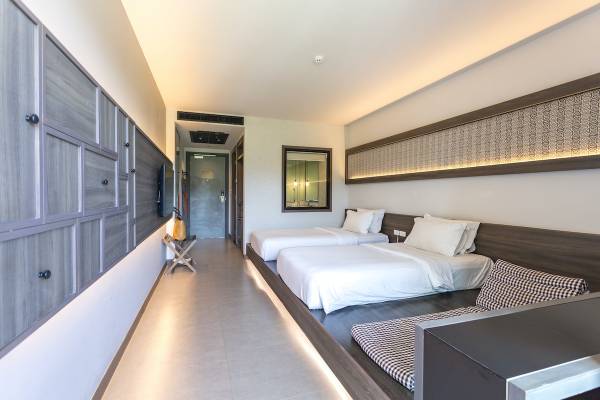 Ein Schlafzimmer im Anana Ecological Resort Krabi mit zwei Betten, weißen Laken und Kissen, einem TV, und dekorativen Wandpaneelen.