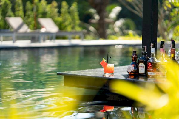 Cocktail am Pool im Anana Ecological Resort Krabi mit Flaschen und Lounge-Liegen im Hintergrund.