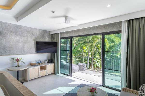 Innenansicht der Suite im Anana Ecological Resort Krabi mit Balkon, Fernseher und Tisch mit Blumen.