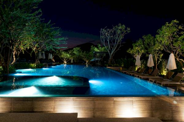 Der Außenpool des Anana Ecological Resort Krabi bei Nacht, beleuchtet und umgeben von Bäumen.
