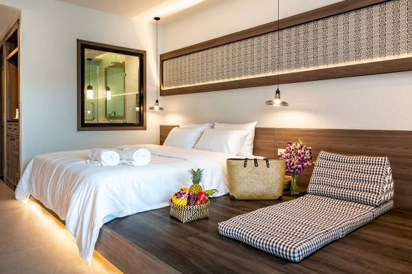 Innenansicht eines Schlafzimmers im Anana Ecological Resort Krabi mit Bett, Früchtekorb und Dekokissen.