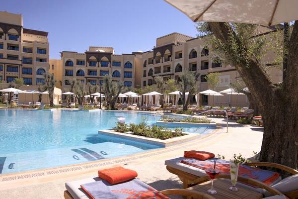 Außenpool des Saadiyat Rotana Resort & Villas mit Sonnenliegen und Schirmen