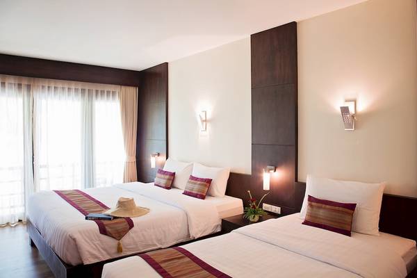 Doppelbett Zimmer im Tup Kaek Sunset Beach Resort mit modernen Möbeln, hellem Licht und Blick auf das Fenster.
