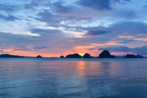 Sonnenuntergang über dem Meer mit mehreren Inseln am Horizont vom Tup Kaek Sunset Beach Resort aus gesehen.